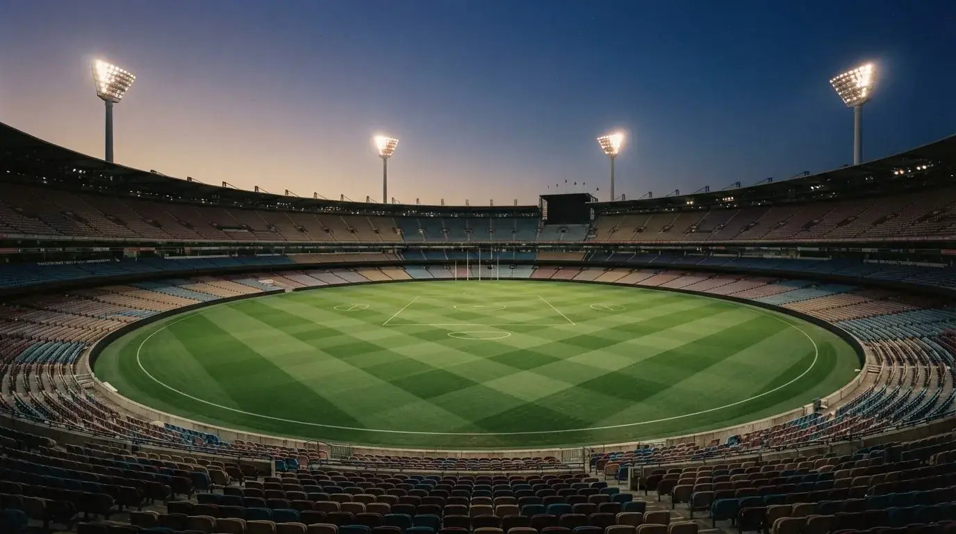 An empty football stadium with floodlight masts at dusk