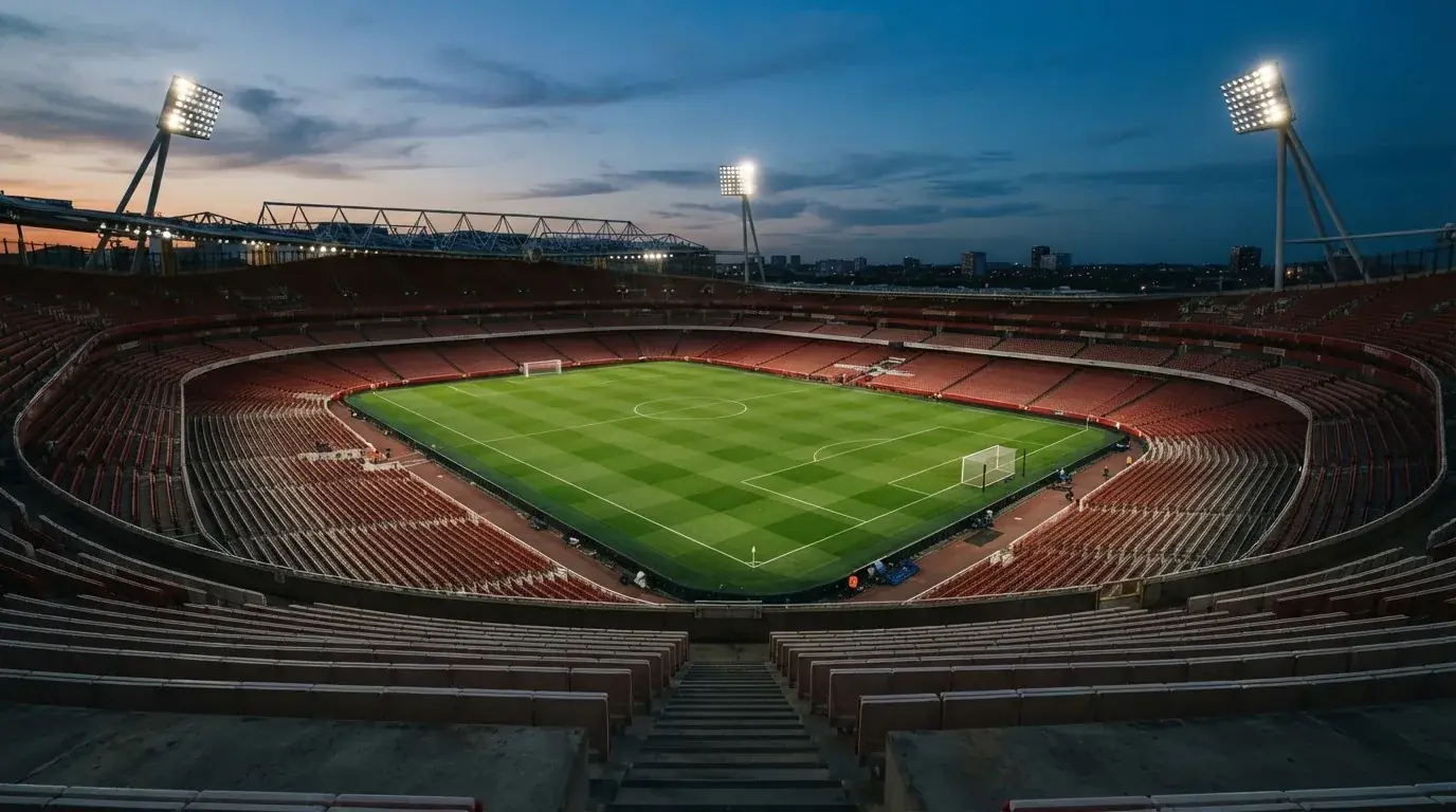 An empty football stadium with floodlight masts at dusk