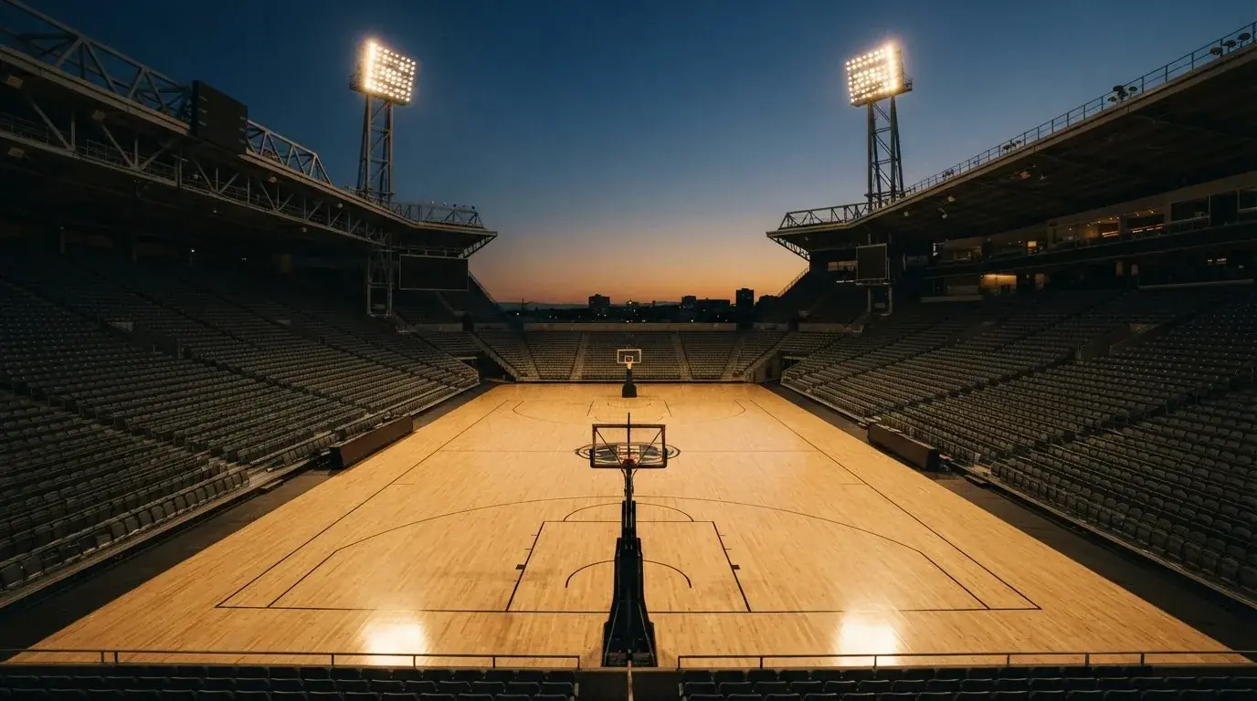 An empty football stadium with floodlight masts at dusk