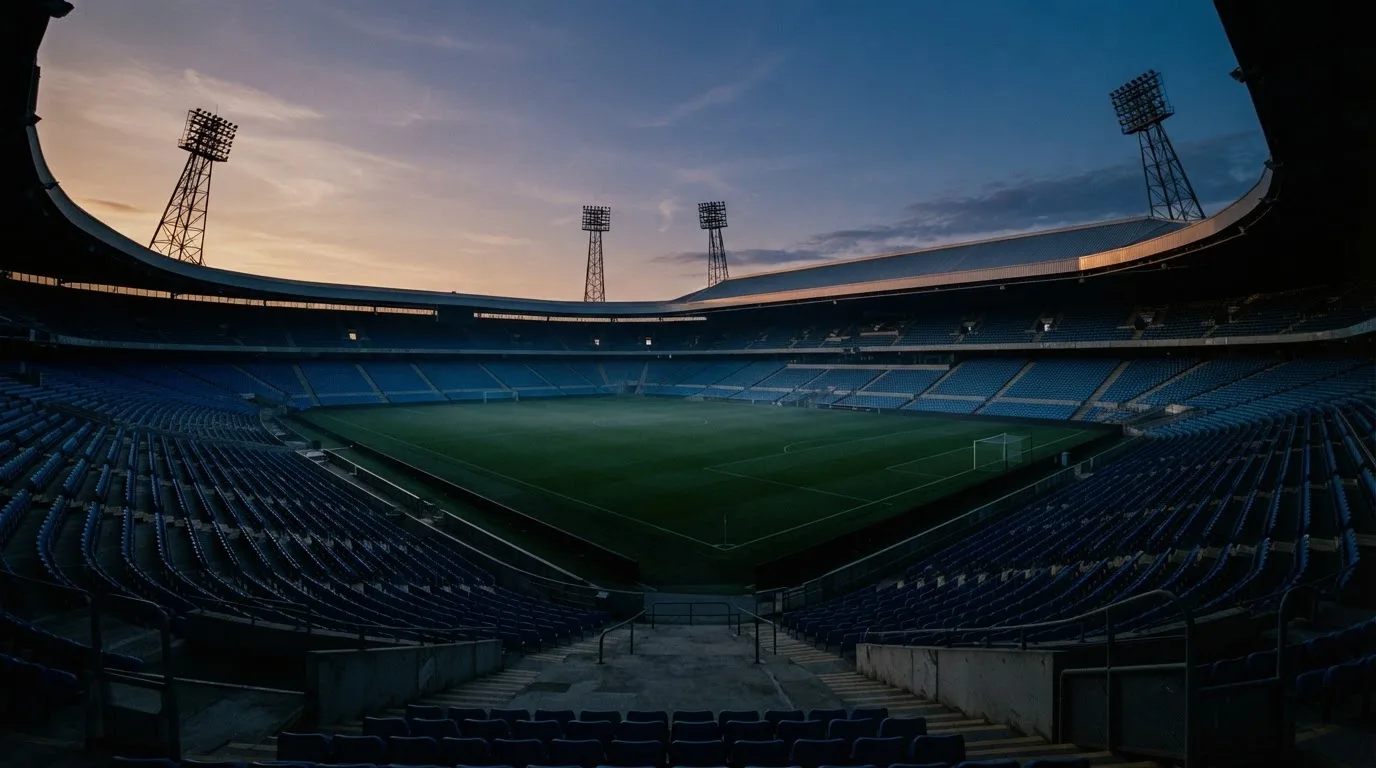 An empty football stadium with floodlight masts at dusk