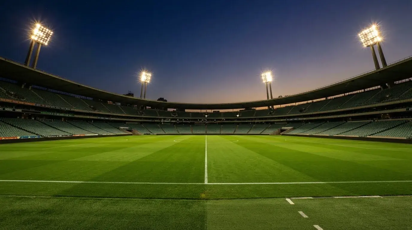 An empty football stadium with floodlight masts at dusk