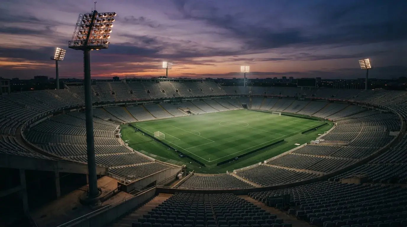 An empty football stadium with floodlight masts at dusk