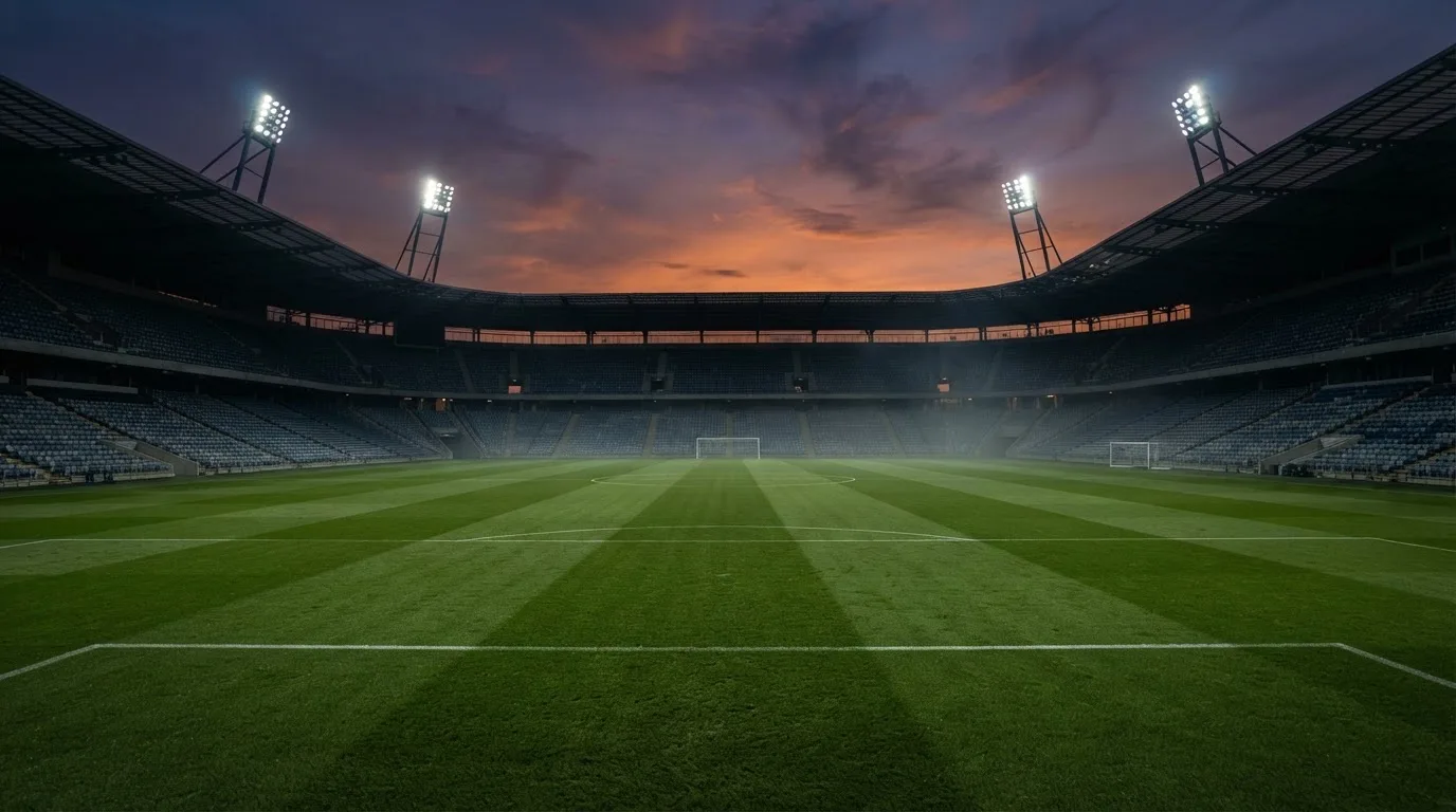 An empty football stadium with floodlight masts at dusk