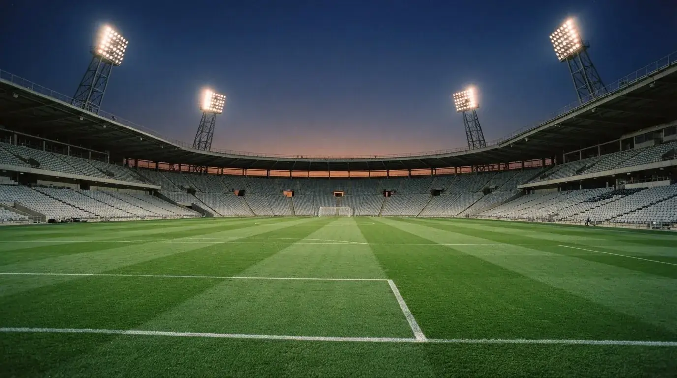 An empty football stadium with floodlight masts at dusk