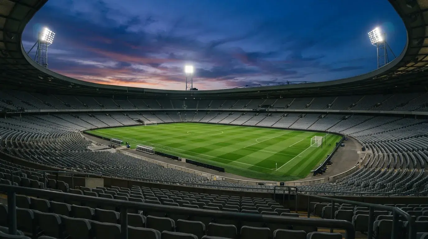 An empty football stadium with floodlight masts at dusk