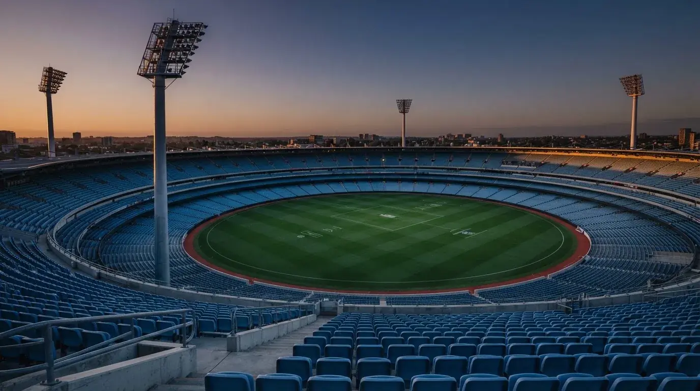 An empty football stadium with floodlight masts at dusk