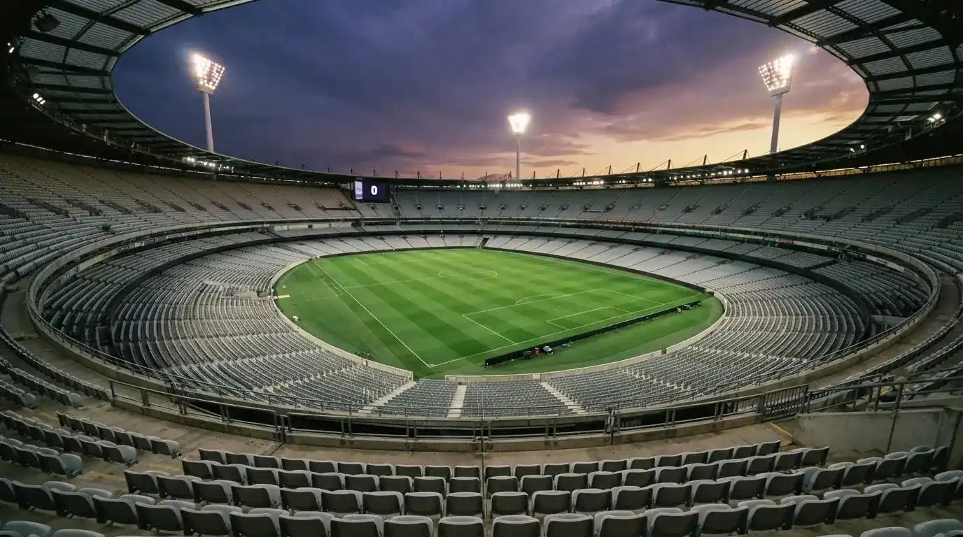 An empty football stadium with floodlight masts at dusk