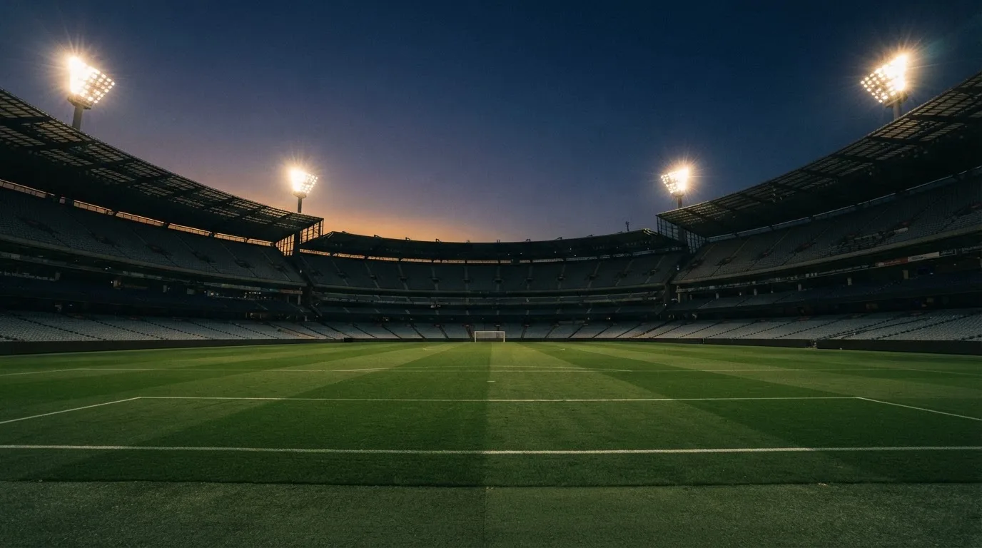 An empty football stadium with floodlight masts at dusk