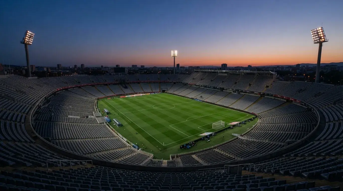 An empty football stadium with floodlight masts at dusk