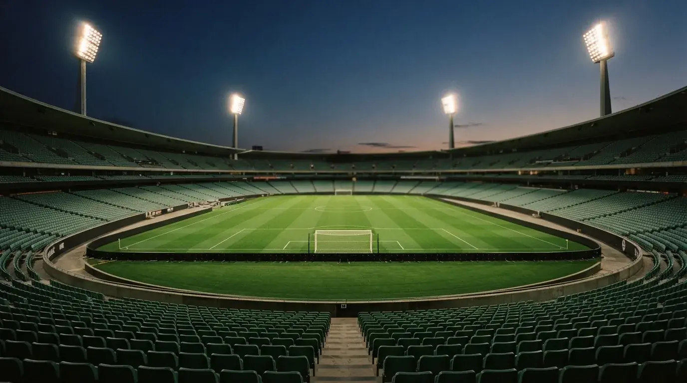 An empty football stadium with floodlight masts at dusk