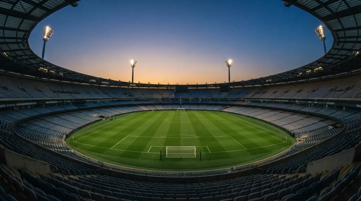 An empty football stadium with floodlight masts at dusk