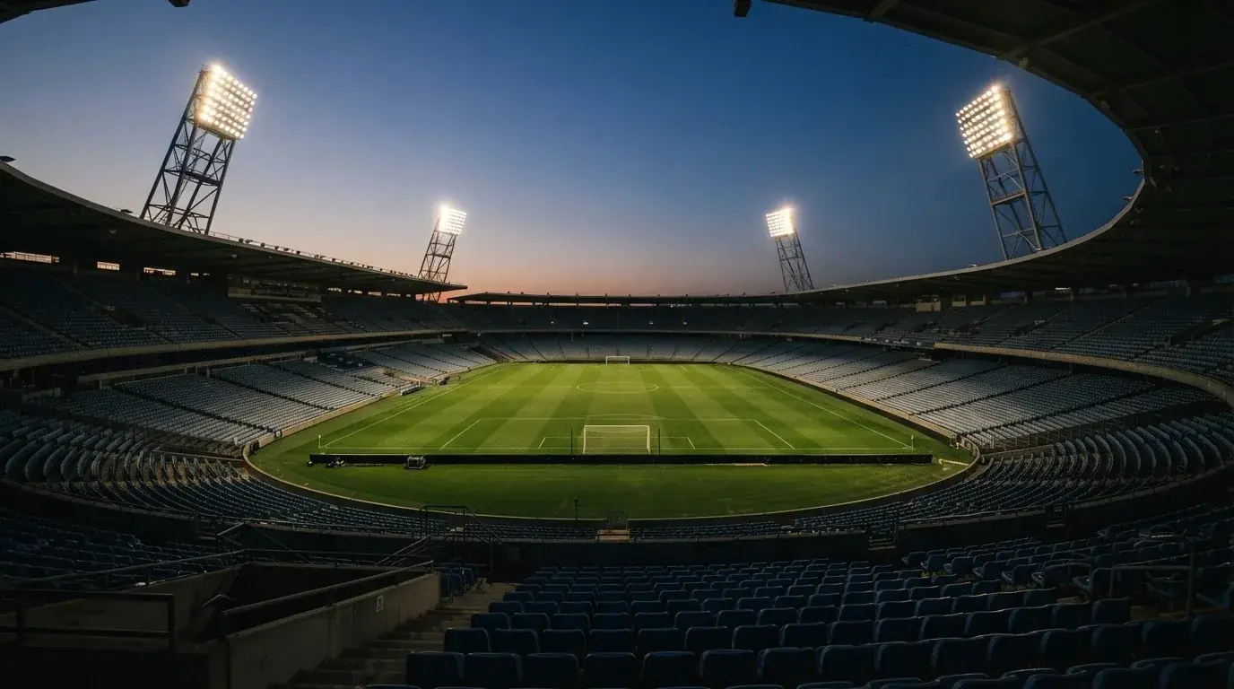 An empty football stadium with floodlight masts at dusk
