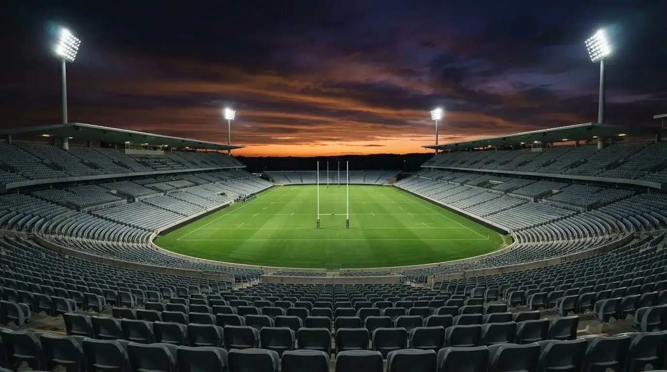 An empty football stadium with floodlight masts at dusk