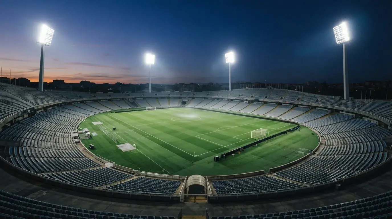 An empty football stadium with floodlight masts at dusk