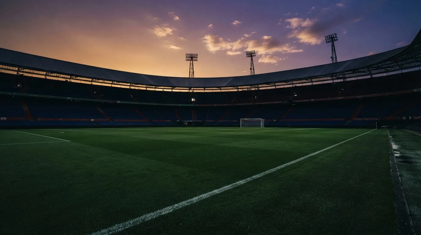 An empty football stadium with floodlight masts at dusk