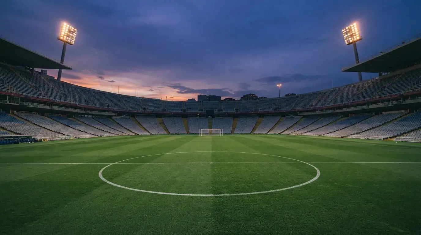 An empty football stadium with floodlight masts at dusk