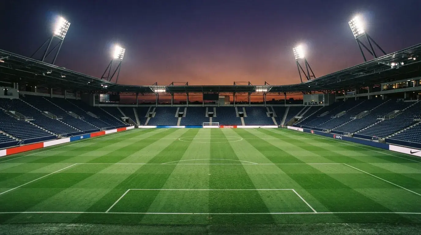 An empty football stadium with floodlight masts at dusk